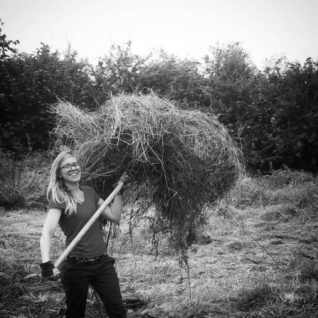 Volunteer Chloe lifts hay
