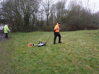 Workers pulling a machine across the ground that surveys for anything underground.