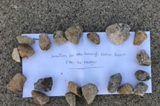 Envelope held down by stones that says 'Donation for Attenborough Nature Reserve'