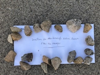 Envelope held down by stones that says 'Donation for Attenborough Nature Reserve'